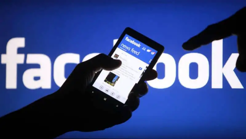 Facebook, uomo con il cellulare in mano