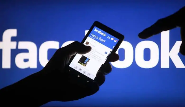 Facebook, uomo con il cellulare in mano