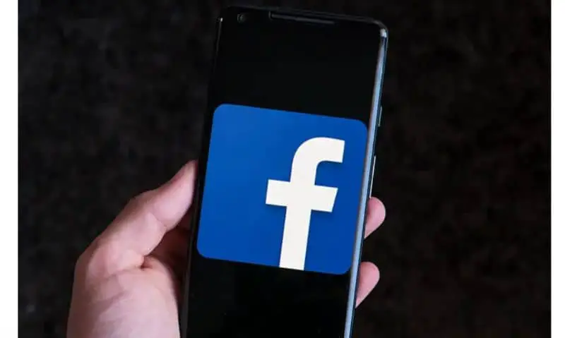 Logo di Facebook, cellulare in mano
