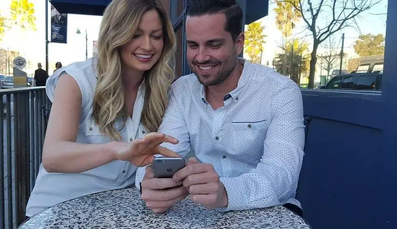 Le coppie ridono insieme guardano il cellulare