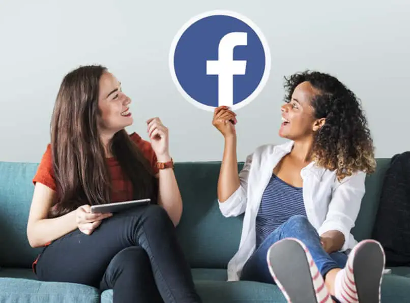 due donne con in mano il logo di facebook