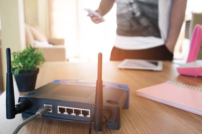 fotografia di un router nero con un cavo grigio che trasmette il segnale wifi a un dispositivo mobile