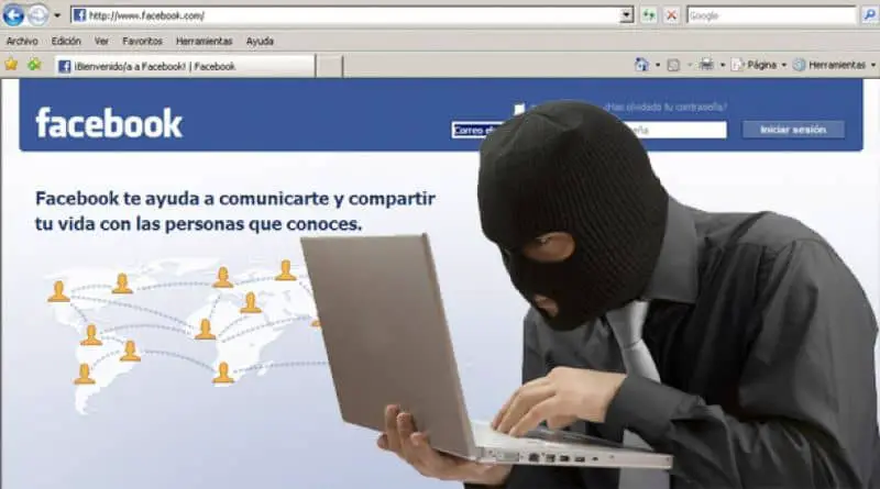 uomo o hacker incappucciato su laptop e sfondo di avvio di Facebook