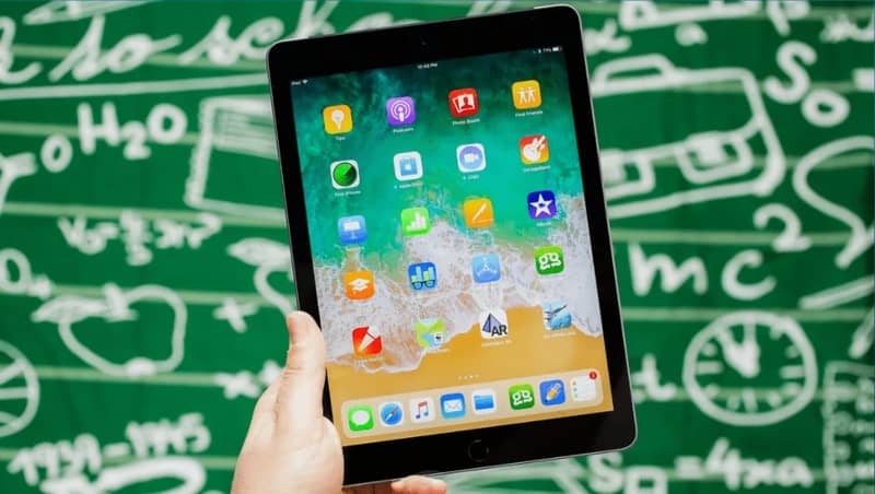 iPad in mano e sfondo di formule matematiche