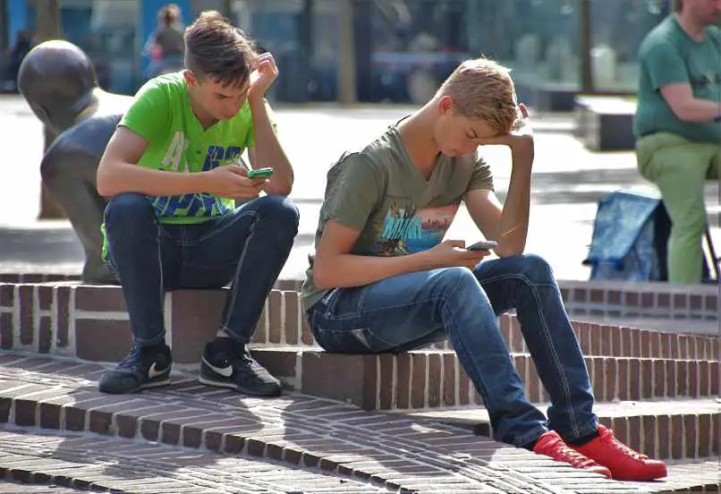 ragazzi seduti in piazza con i cellulari
