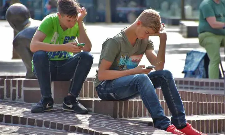 ragazzi seduti in piazza con i cellulari