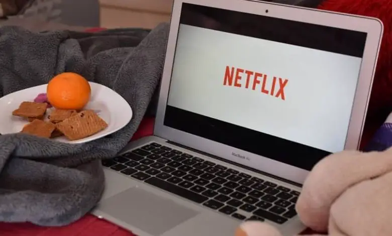 laptop su netflix con un piatto di cibo accanto