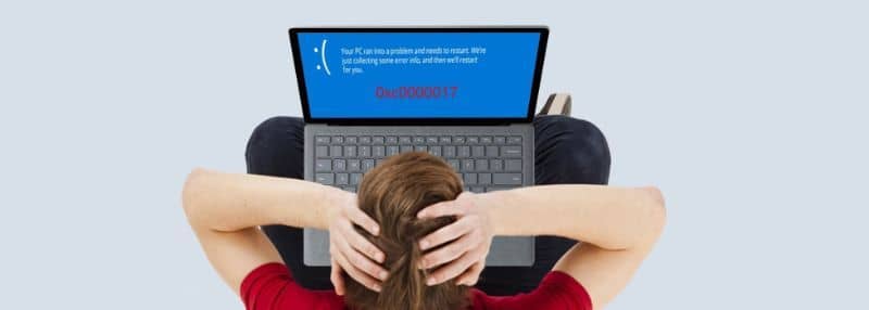 persona che tiene la testa vedendo un errore sul laptop