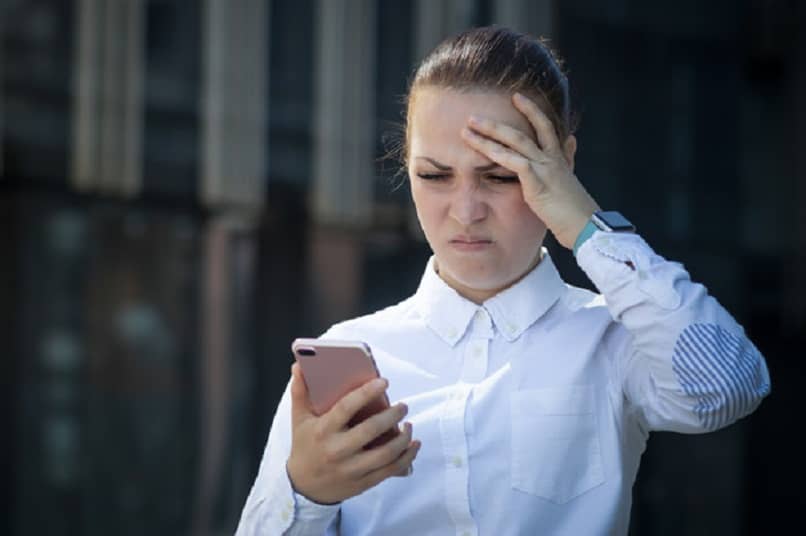 donna frustrata che guarda il suo cellulare