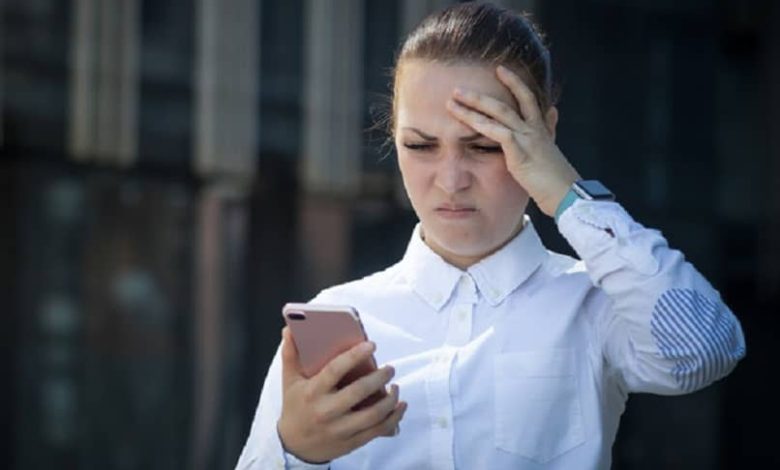 donna frustrata che guarda il suo cellulare