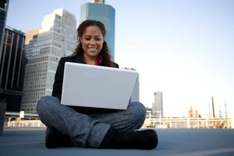 donna seduta felice che guarda usando il laptop