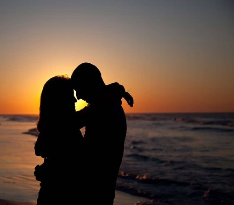 coppia innamorata su una spiaggia con il tramonto sullo sfondo 